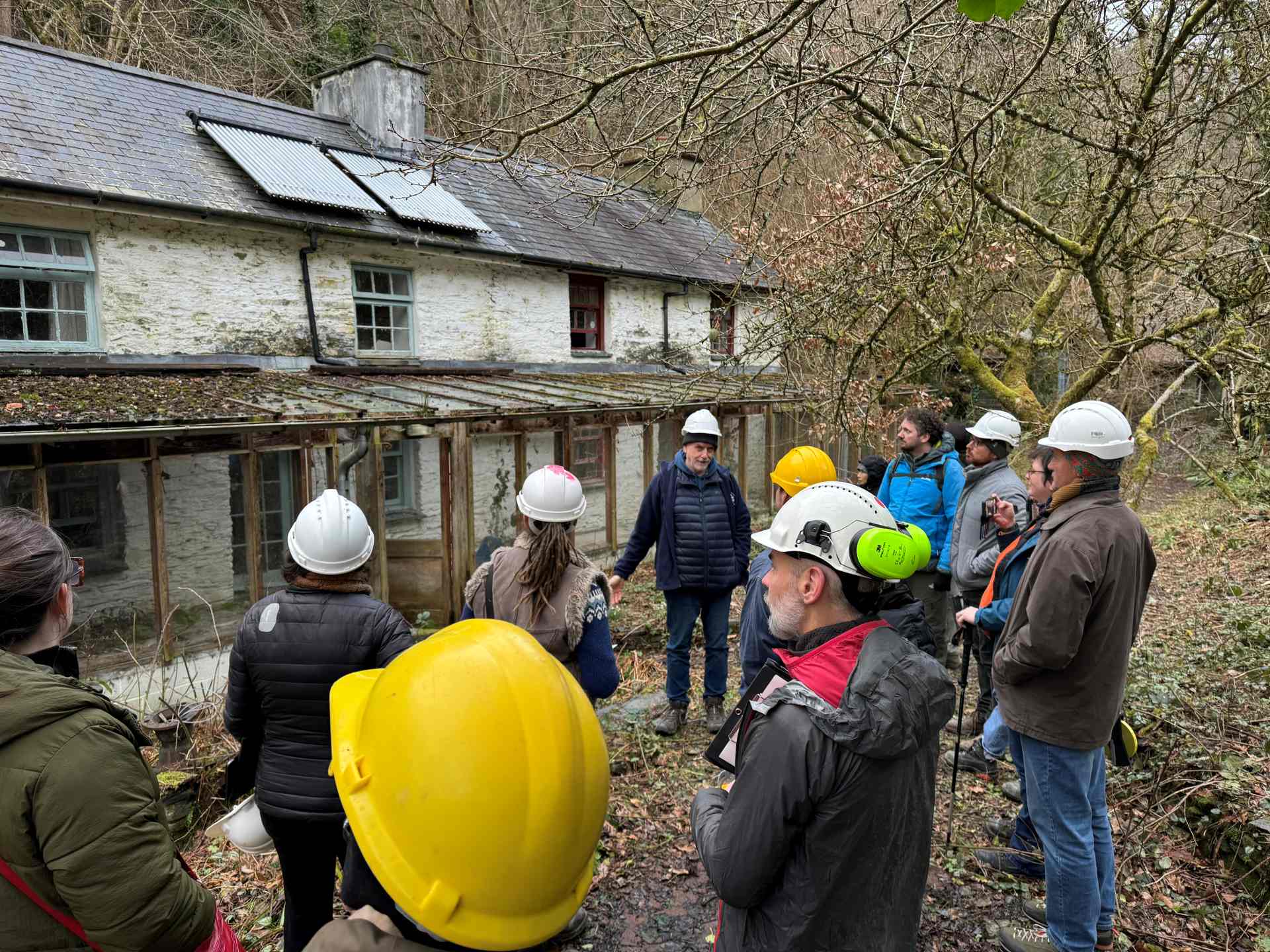 Myfyrwyr ôl-raddedig CyDA yn dysgu o'r gwaith cynllunio ac arolygu parhaus sy'n digwydd cyn adnewyddu y Bythynnod Chwarel sydd heb eu meddiannu ar hyn o bryd ar y safle.